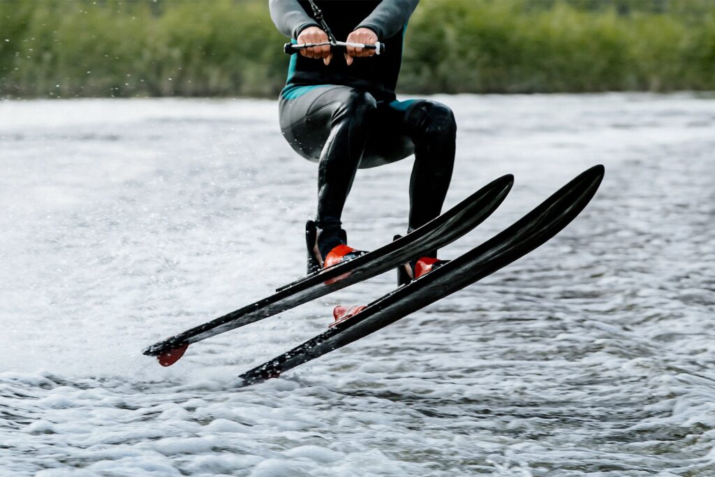 athlete jump waterskiing behind motor boat on lake, extreme summer water sports